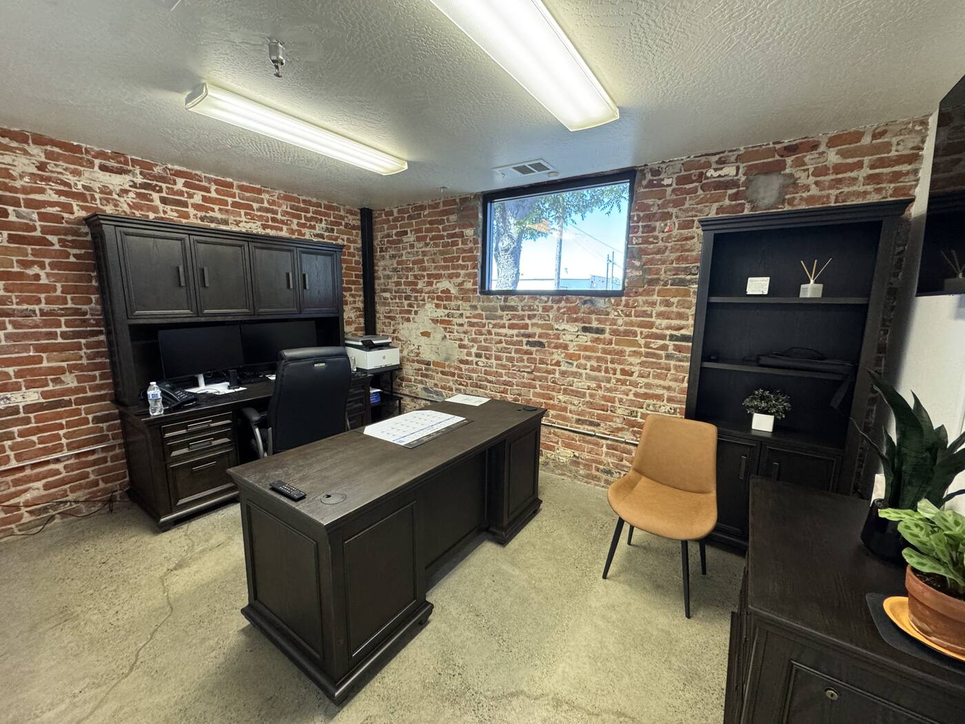 Valley Roots Realty private office — exposed brick wall and wooden desk